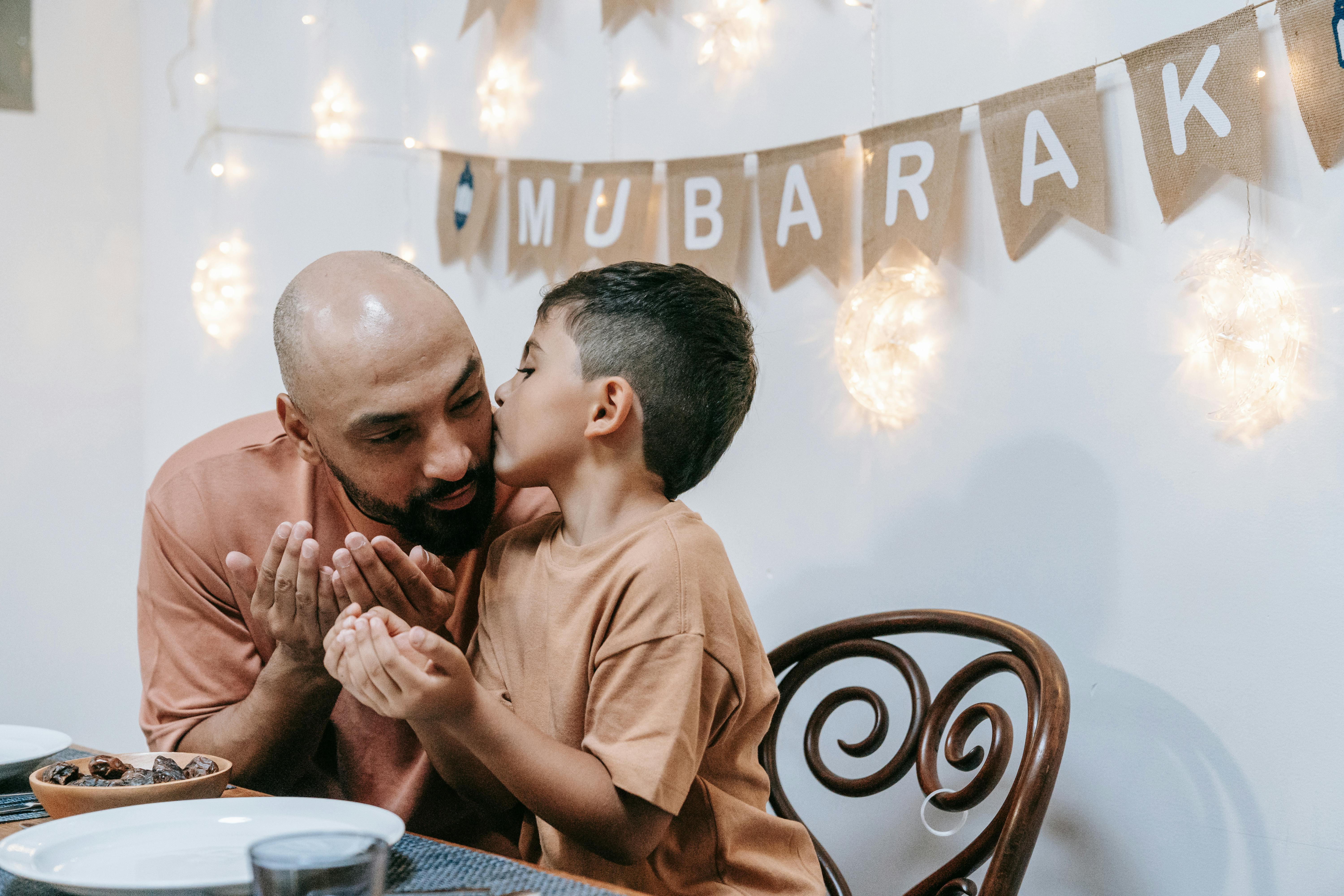 A touching moment between a father and son during an Eid Mubarak celebration indoors.